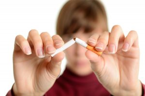 Young woman breaking cigarette over white background